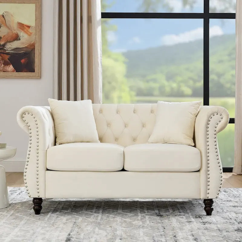 Canapé deux places Chesterfield en velours beige, accoudoirs roulés, garniture cloutée