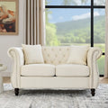 Canapé deux places Chesterfield en velours beige, accoudoirs roulés, garniture cloutée