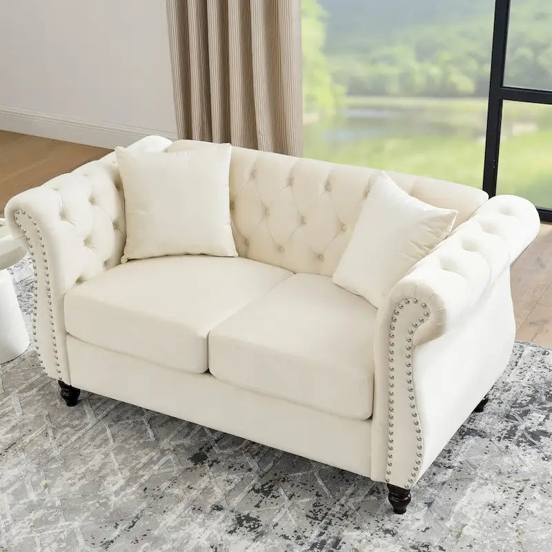 Canapé deux places Chesterfield en velours beige, accoudoirs roulés, garniture cloutée