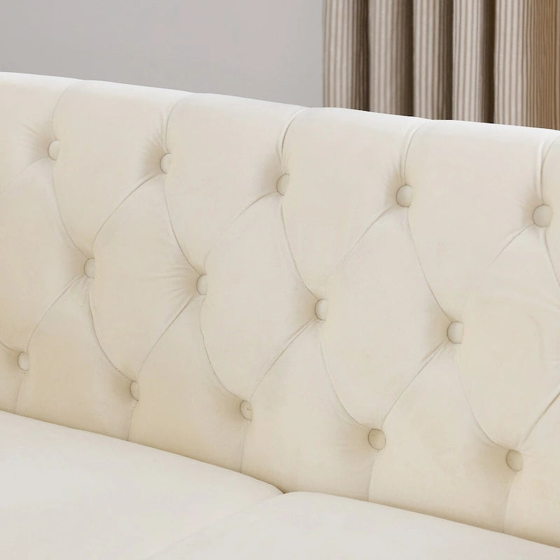 Canapé deux places Chesterfield en velours beige, accoudoirs roulés, garniture cloutée
